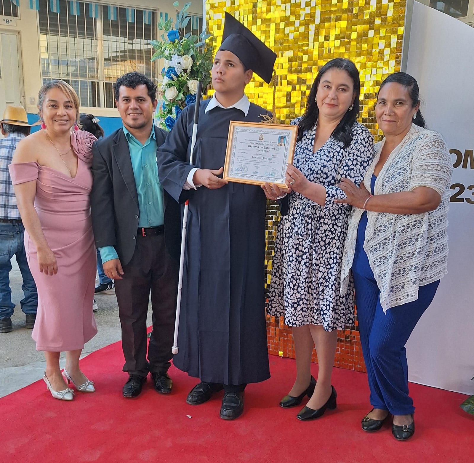 Assistant Director, Prof. Cindy, stands between Luis Daniel and his mother Sandra as she presents the diploma certifying Luis Daniel’s completion of junior high. Alongside them are Edelberto Andino from Shoulder to Shoulder and Prof. Eva, the school’s director, proudly celebrating this achievement.